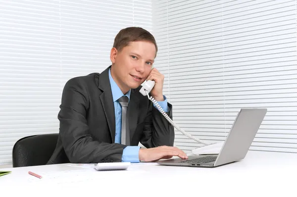 Hombre de negocios que trabaja en el ordenador portátil en la oficina y llamando a — Foto de Stock