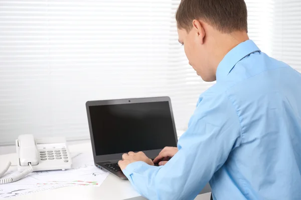 Bakre syn på en ung affärsman arbetar på en bärbar dator — Stockfoto