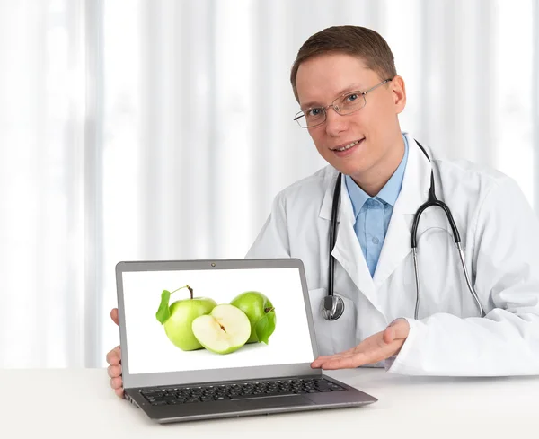 Orvos, zöld alma mutatja a laptop számítógép — Stock Fotó