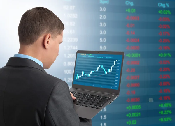 Empresário com laptop no fundo do mercado de ações — Fotografia de Stock
