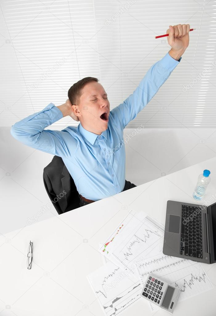 Young business man stretching his arms while yawning