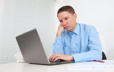 Genç adam dizüstü bilgisayarla çalışıyor.