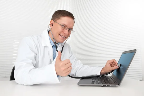 Arts met een stethoscoop reparatie een laptop Stockafbeelding