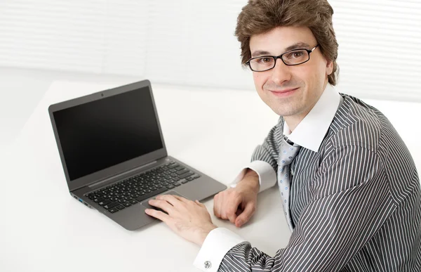 Mladý obchodník pomocí notebooku a usmívá se — Stock fotografie