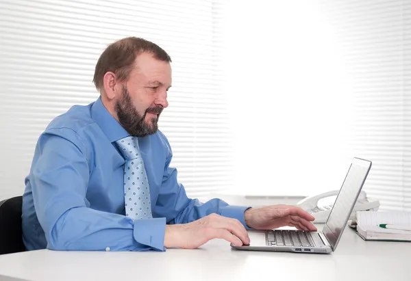 Seniorunternehmer sitzt an seinem Laptop im Büro — Stockfoto