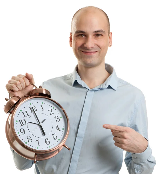 Smiling guy pointing on a big alarm clock — Stock Photo, Image