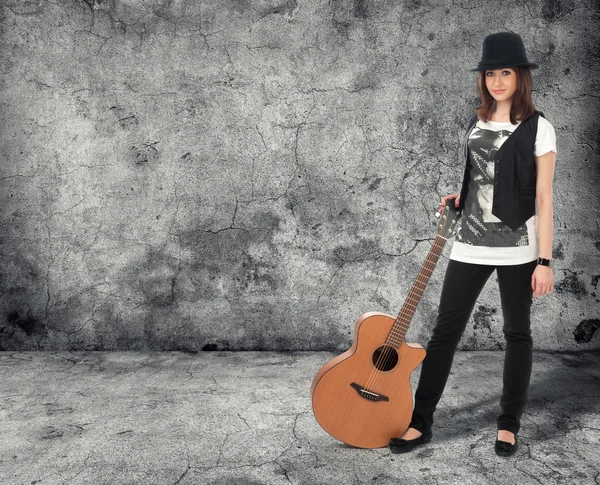 Ragazza con la chitarra. muro di cemento grigio — Foto Stock