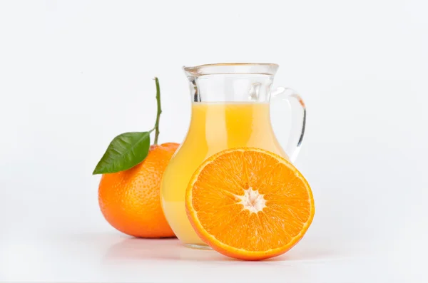 Orange juice in pitcher and oranges — Stock Photo, Image