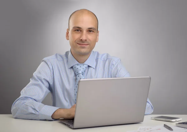 Handsome young business man in office with laptop Stock Image