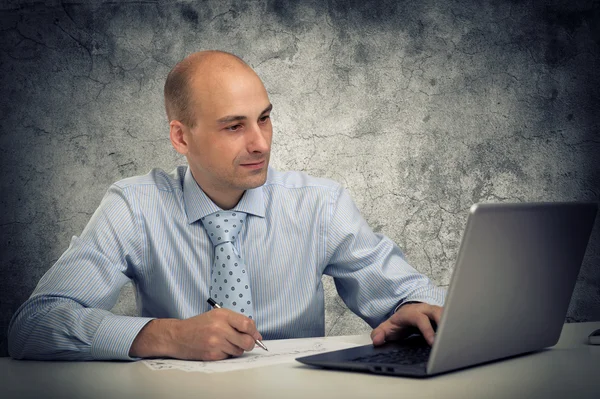 Zakenman met een laptop zit aan zijn Bureau — Stockfoto