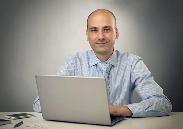 Handsome young business man in office with laptop Stock Picture