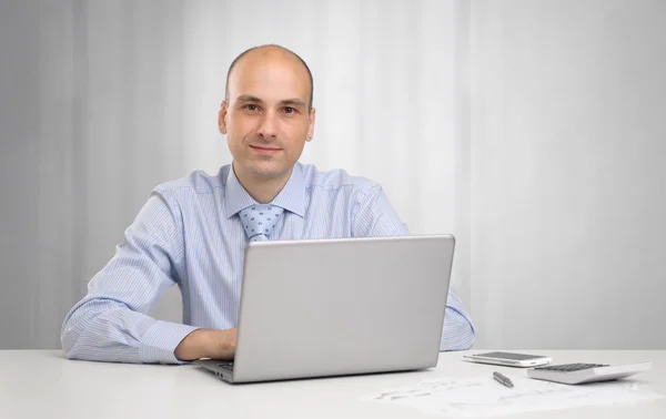 Handsome businessman sitting at desk in office, working on lapto Royalty Free Stock Images