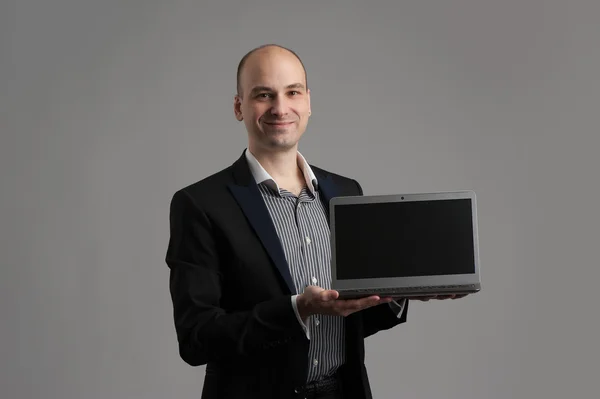 Homem bonito sorrindo mostrando laptop — Fotografia de Stock