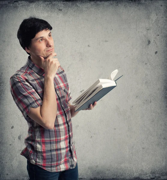 Pensativo homem adulto médio com livro olhando para cima — Fotografia de Stock