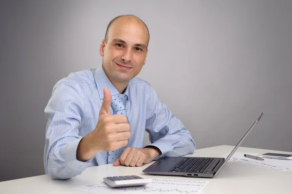 Business man working on laptop and making the ok gesture Stock Image