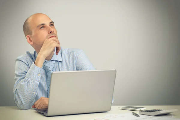 Pensativo hombre de negocios que trabaja en una computadora portátil —  Fotos de Stock
