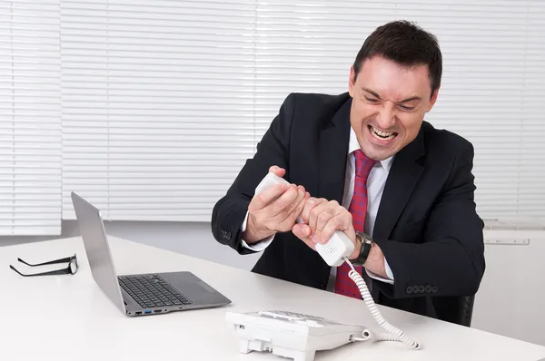 Boos zakenman gillend op telefoon in zijn kantoor — Stockfoto