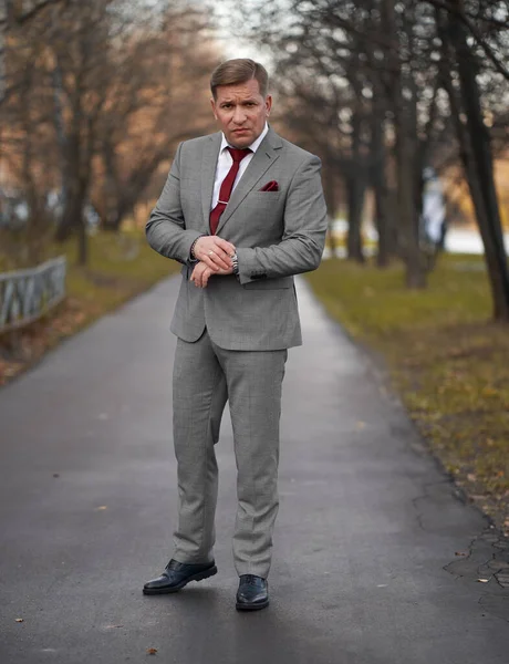 40歳の男は灰色のスーツと赤いネクタイ屋外の肖像画を着ています — ストック写真