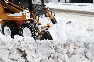 Sarı traktör bir sokakta kar temizleme