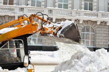 Sarı traktör bir sokakta kar temizleme