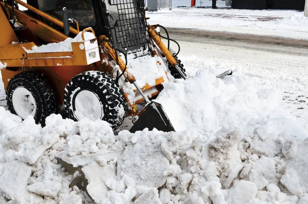 Gelber Traktor reinigt den Schnee auf einer Straße — Stockfoto