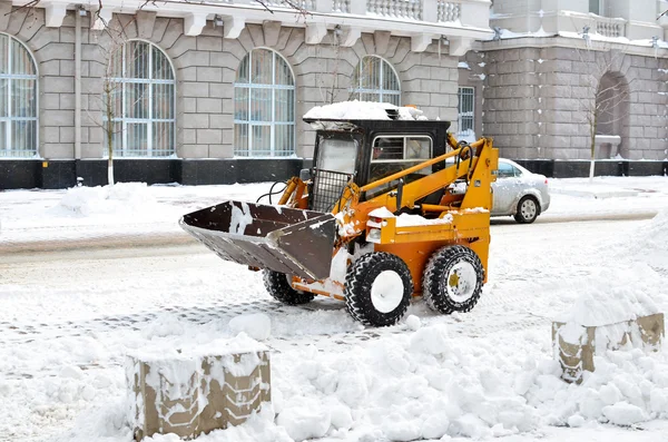 Tractor amarillo limpiando la nieve en una calle —  Fotos de Stock