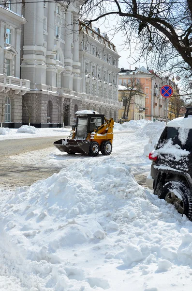 Gele trekker reiniging van de sneeuw op een straat — Stockfoto