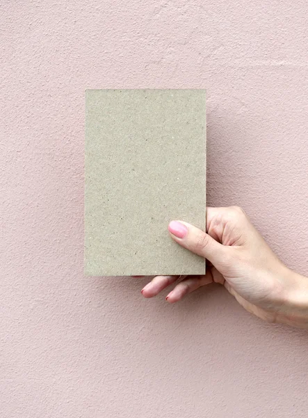 Tarjeta de felicitación en mano de mujer sobre fondo de pared — Foto de Stock