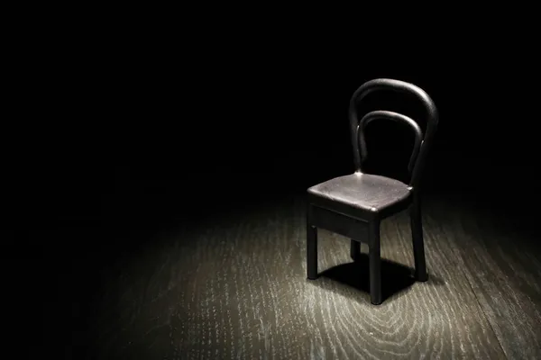 在昏暗的房间里 明亮的灯光下 一张空的黑椅子 — 图库照片