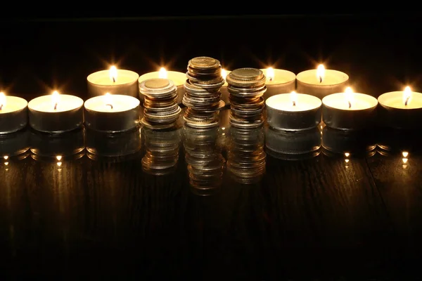 Ein Satz Münzen Zwischen Brennenden Kerzen Auf Dunklem Hintergrund Stockbild