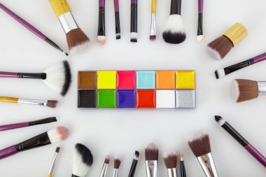 Beyaz arka planda makyaj fırçaları ve kozmetik ürünleri