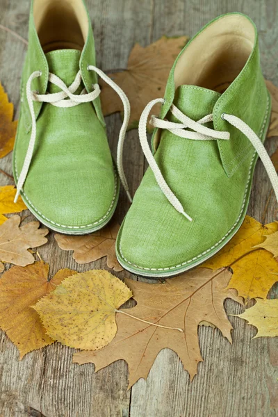 Botas de cuero verde y hojas amarillas — Foto de Stock