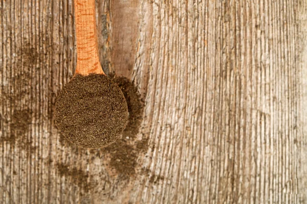 Ground black pepper in wooden spoon — Stock Photo, Image