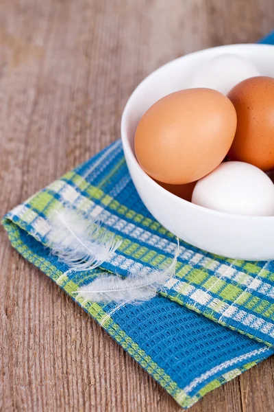 Яйца в миске, полотенце и перья — стоковое фото