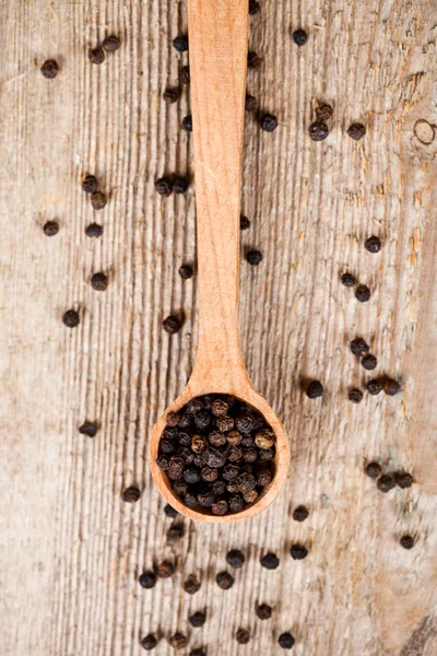 Pimienta negra en cuchara de madera — Foto de Stock