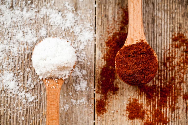 Ground red pepper and cooking salt in wooden spoons — Stock Photo, Image