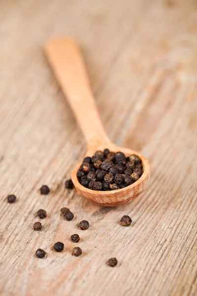 Black pepper in wooden spoon — Stock Photo, Image