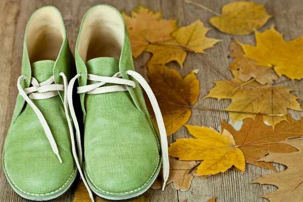 Par de botas de cuero verde y hojas amarillas —  Fotos de Stock