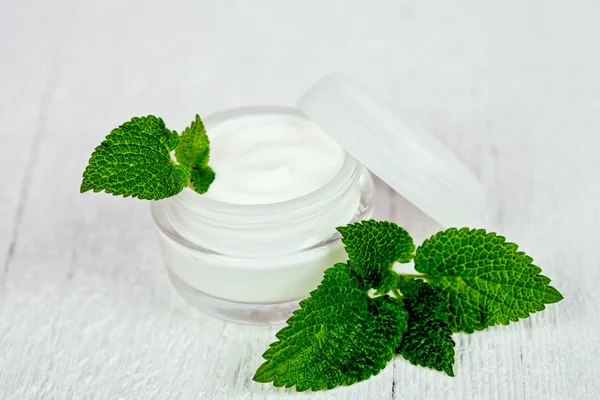 Face cream in glass jar with green leaf of urtica — Stock Photo, Image