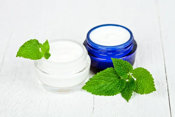 Face cream in jars with urtica leaves — Stock Photo, Image