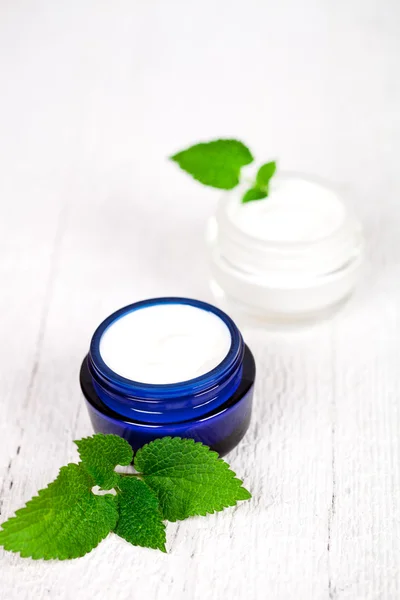 Face cream in jars with urtica leaves — Stock Photo, Image