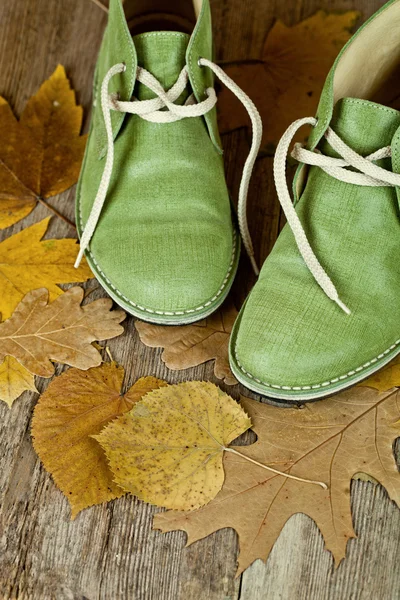 Par de botas de cuero verde y hojas amarillas —  Fotos de Stock