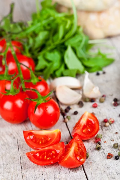 Färska tomater, vitlök, rucola, pepparkorn och bullar — Stockfoto