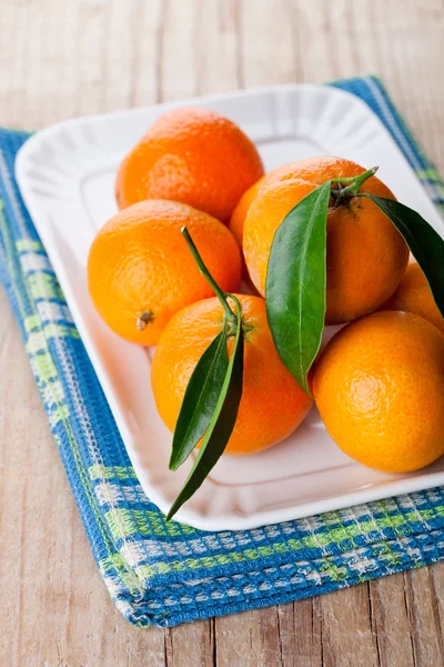 Mandarinen mit Blättern im Teller — Stockfoto