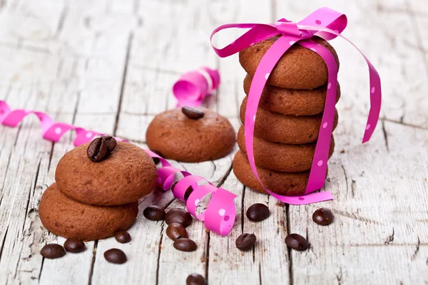 Stapel Schokoladenkekse mit rosa Schleife und Kaffeebohnen — Stockfoto