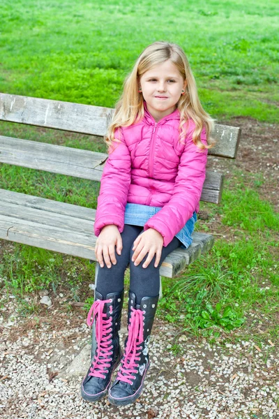 Girl sitting on a bench in the park — Stock Photo, Image