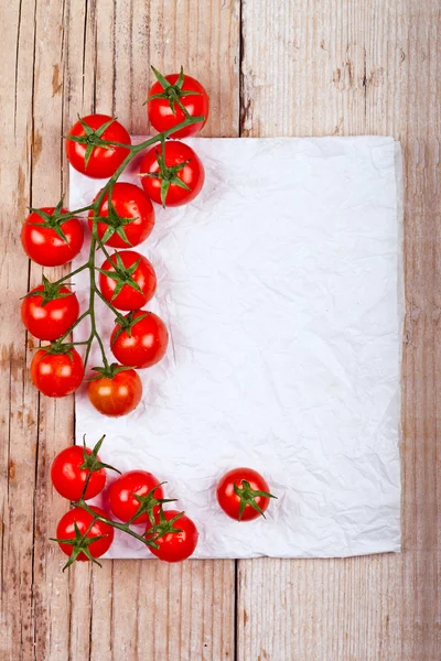 Tomates cereja frescos e pedaço de papel — Fotografia de Stock