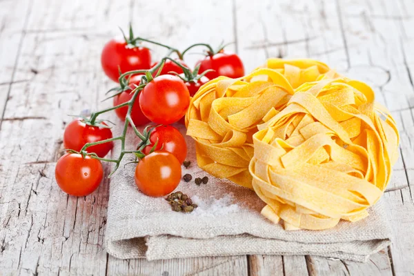 Uncooked pasta and fresh tomatoes — Stock Photo, Image