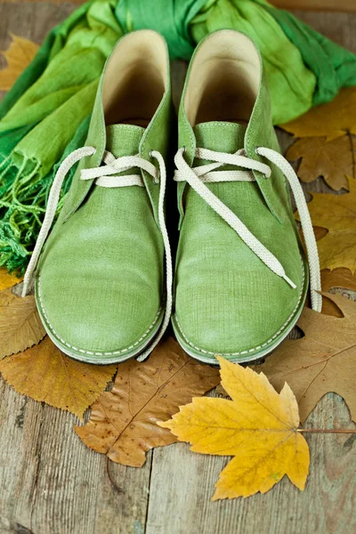 Par de botas de cuero verde, bufanda y hojas amarillas —  Fotos de Stock