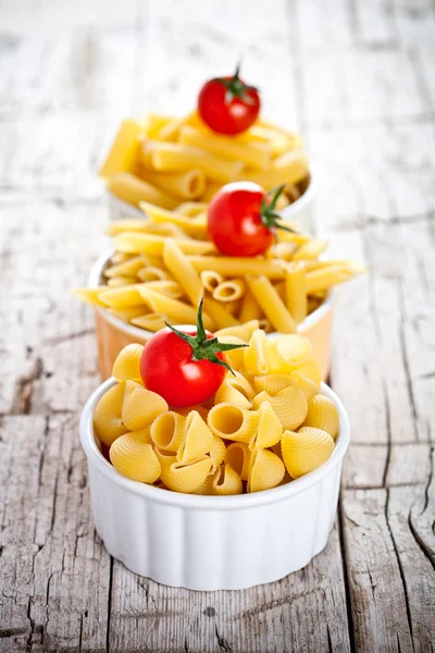 Uncooked pasta and cherry tomatoes in three bowls — Stock Photo, Image